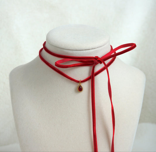 Red choker necklace on a mannequin bust against a white background