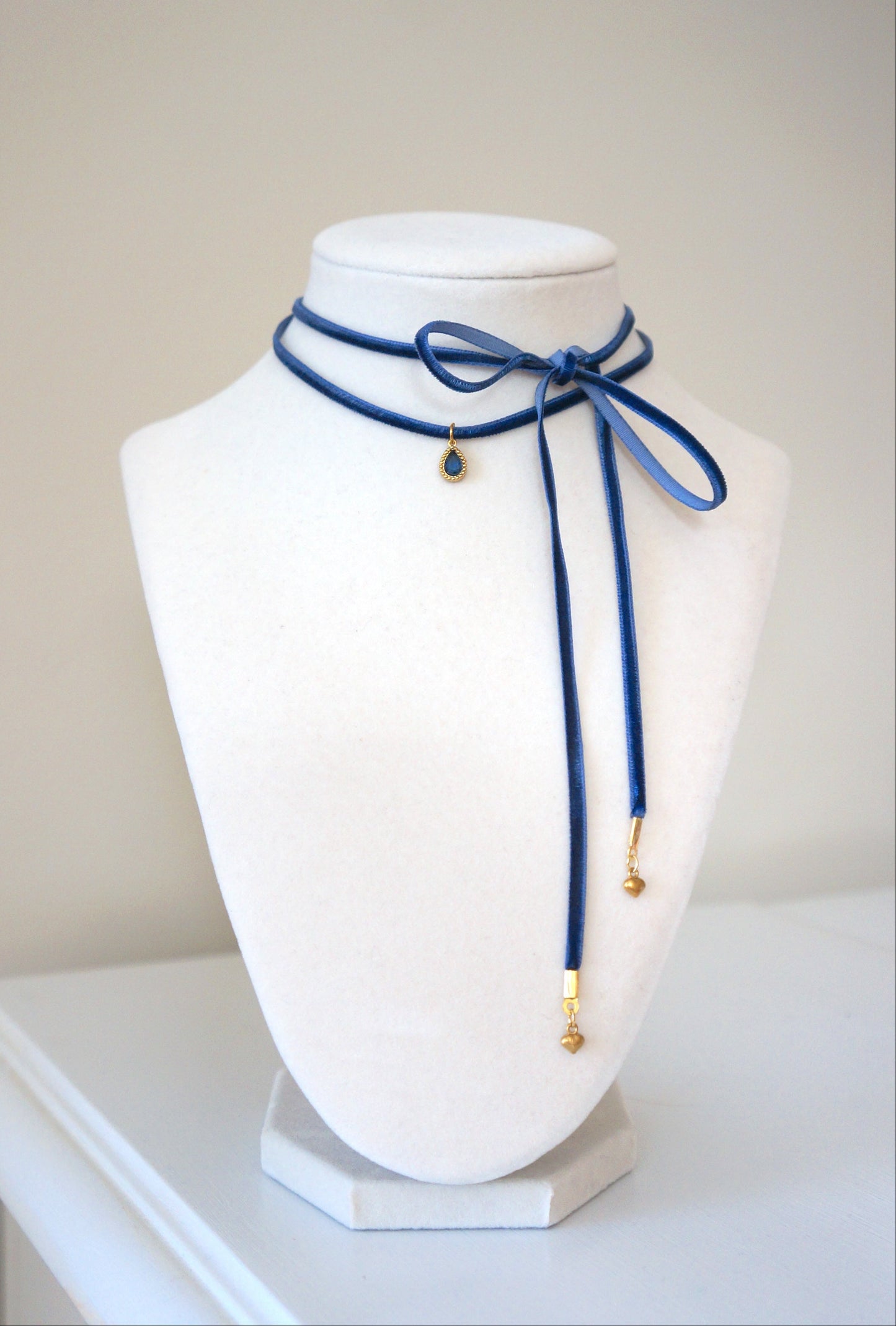 Navy blue necklace on a white mannequin bust against a plain background